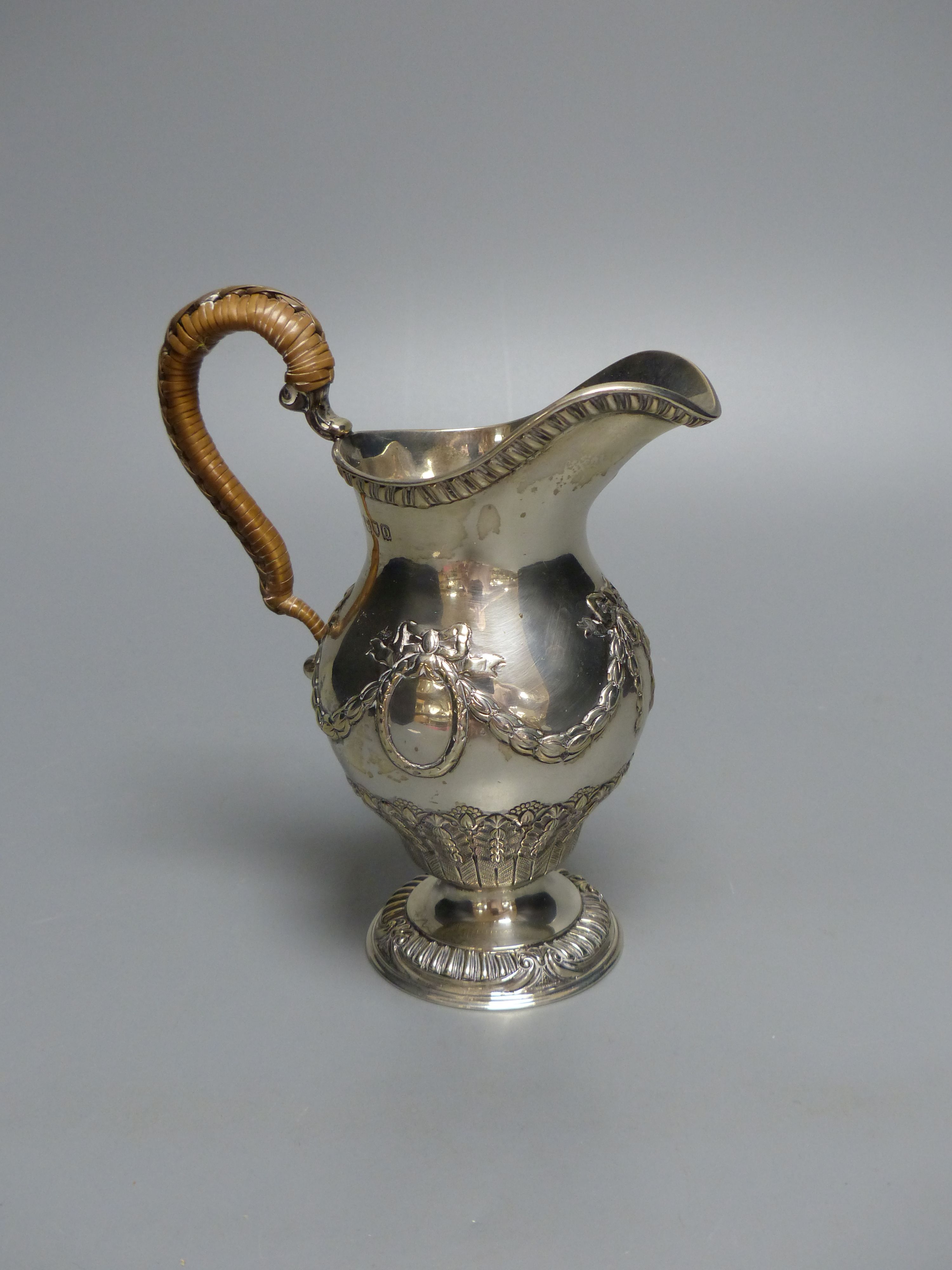 An Edwardian silver cream jug, with rattan handle, Goldsmiths & Silversmiths Co Ltd, London, 1909, 15.5cm, 8oz.